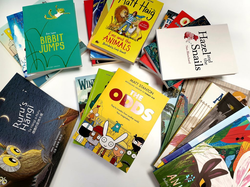 Several piles of brand-new children's books, including picture books, fiction, nonfiction, and comics