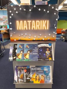A display of face-out childrens books about Matariki beneath a colourful sign decorated with silver star bunting.