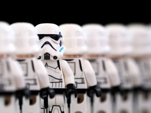 A row of Stormtrooper minifigs face away from the viewer, except the second in the row which is turned to face forward.