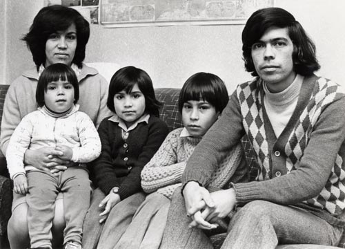 a family with 3 children sit facing the camera. Black and White image.