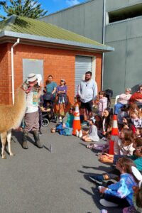 Man with guanaco, watched by children