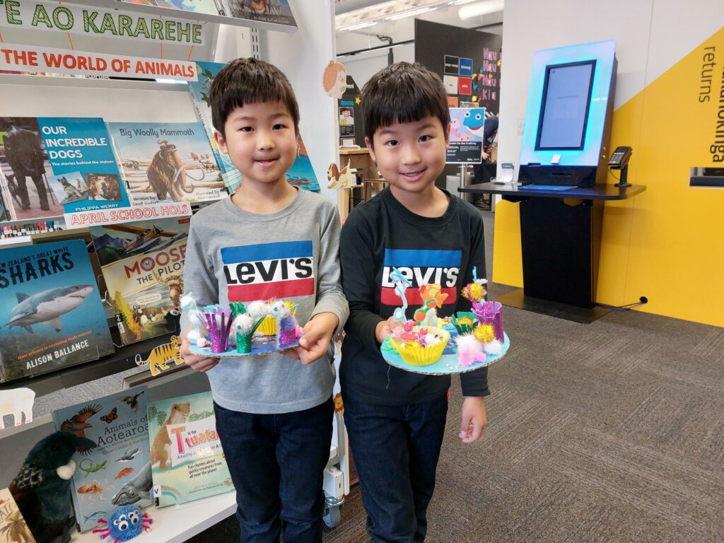 Two boys hold artwork