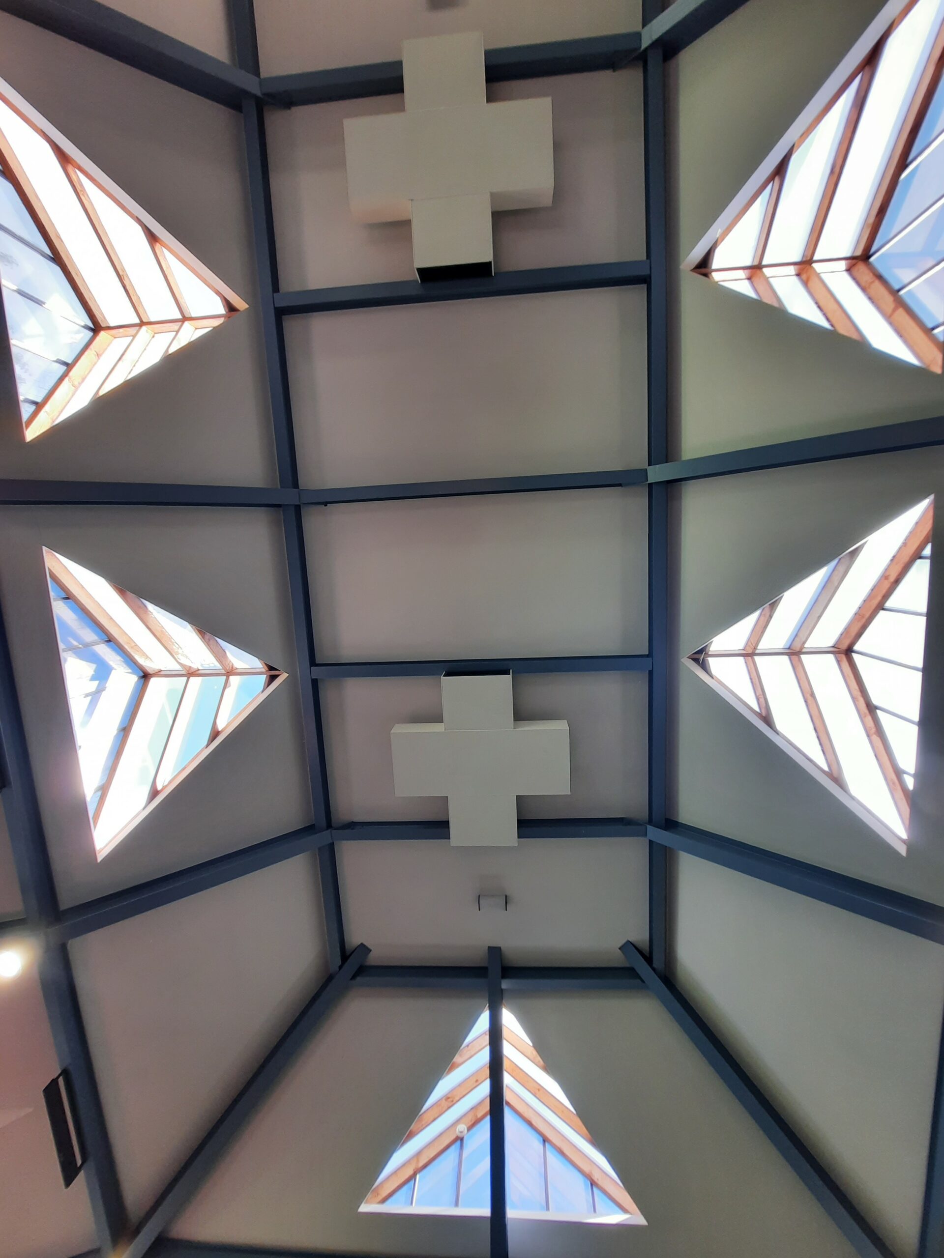 Vaulted ceiling with triangular recessed skylights pointing inwards.