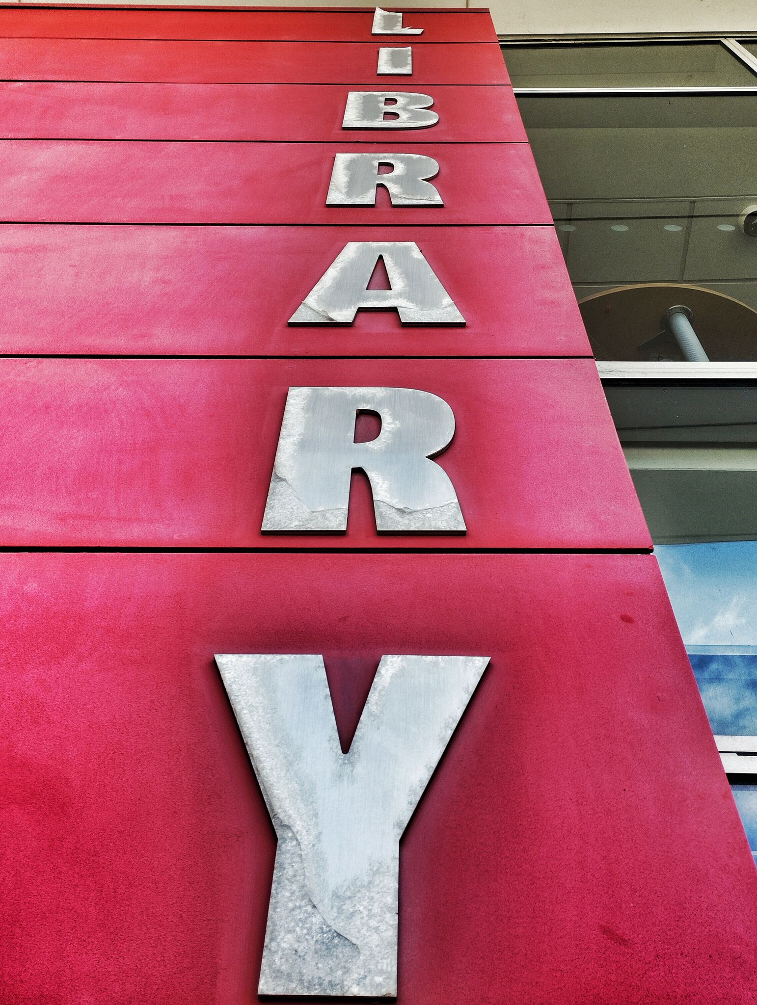 Looking upwards at the vertical word 'Library' on a red background.