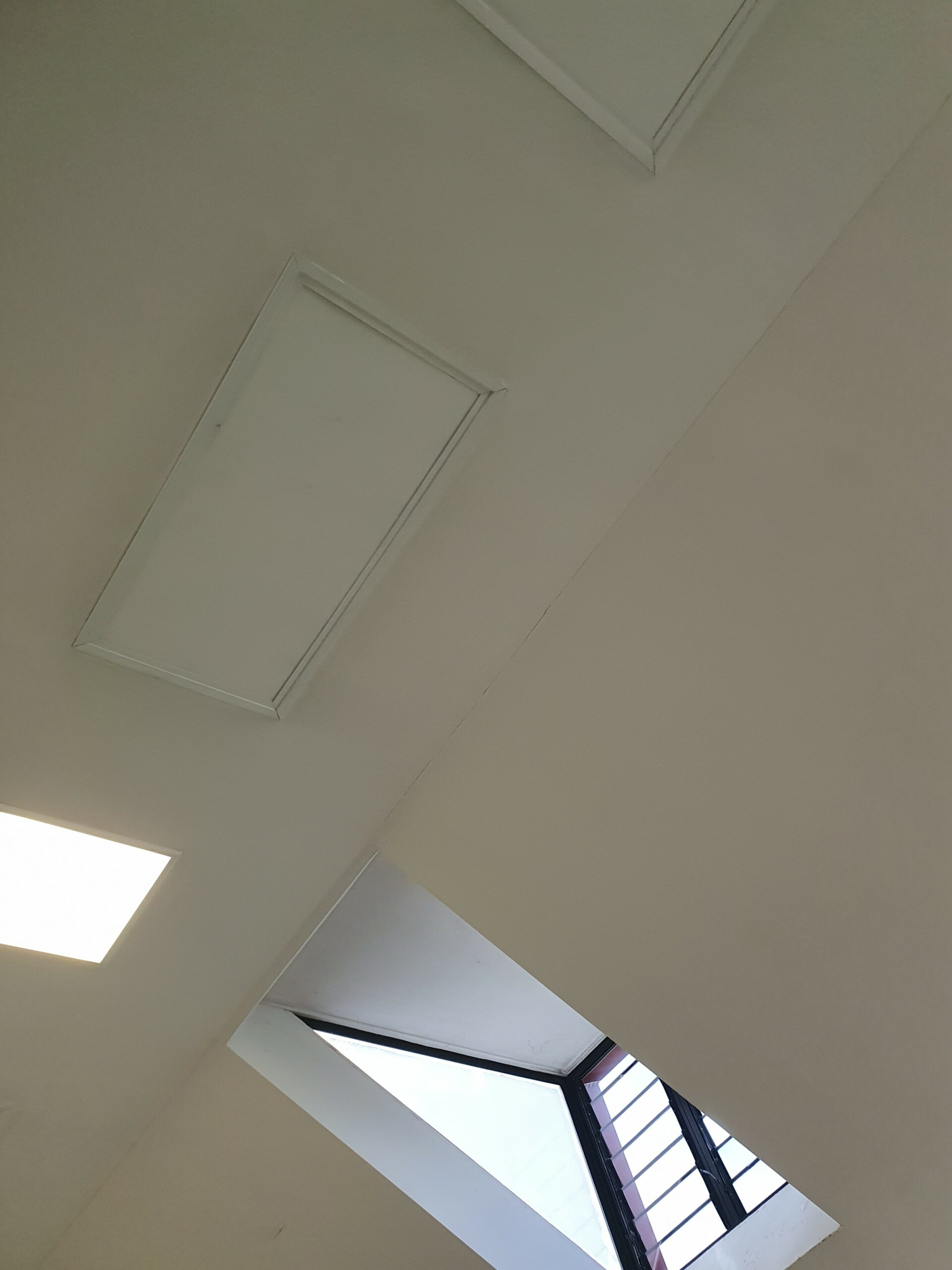 Diagonal angular ceiling line, with a square light in the ceiling and recessed skylight